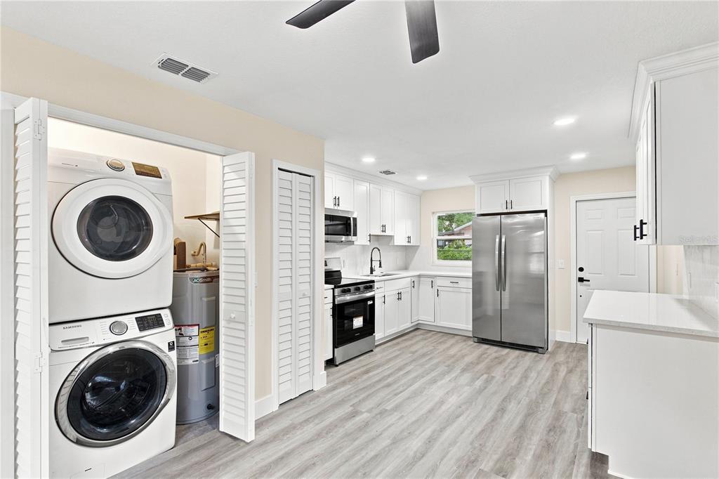 A living room with light-colored walls, gray wood-look flooring, a ceiling fan, and front door — 1105 PARK STREET, SEFFNER, FL