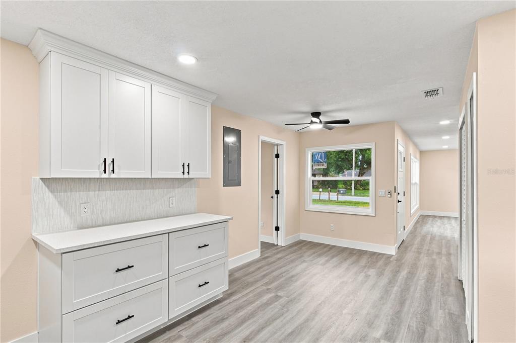 A kitchen features white cabinets, stainless steel appliances, light wood flooring, and an integrated laundry closet — 1105 PARK STREET, SEFFNER, FL