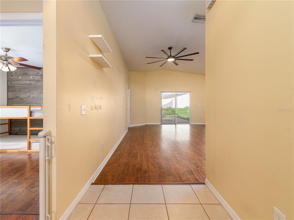 A view from a tiled entryway into a living area with wood-look flooring and sliding doors — 37154 HIGHLAND BLUFF CIRCLE, DADE CITY, FL