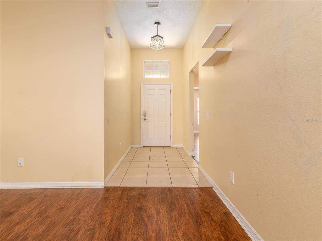 An entryway features a tiled floor, a white front door, and a hanging light fixture — 37154 HIGHLAND BLUFF CIRCLE, DADE CITY, FL