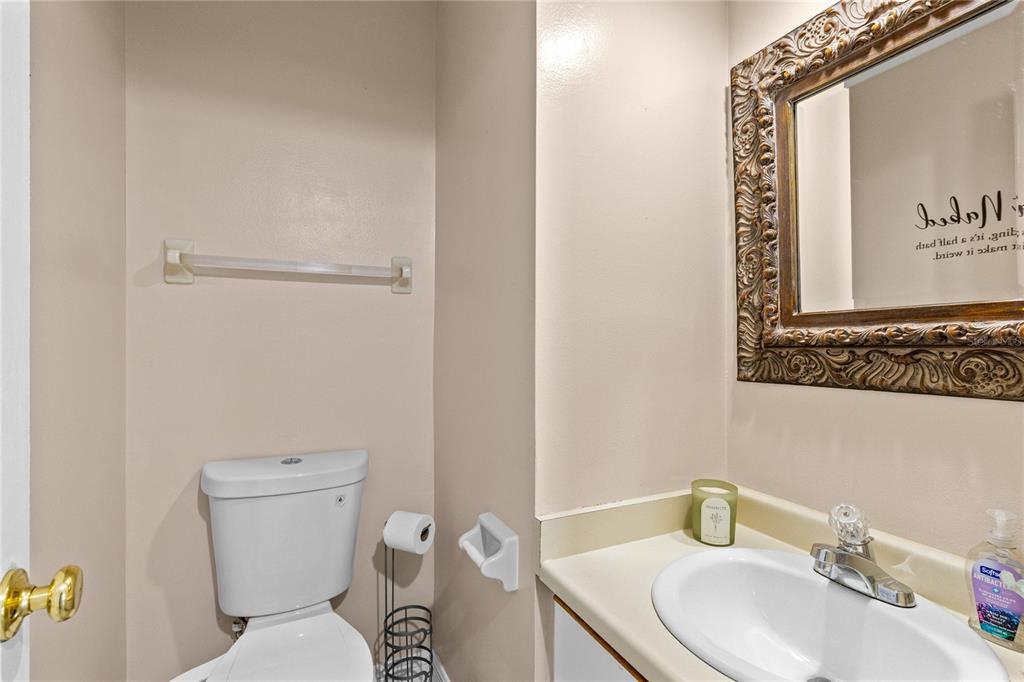 A small bathroom features a white toilet, a vanity with a sink, and a framed mirror — 3307 AMBER WOOD WAY UNIT 106, WINTER PARK, FL