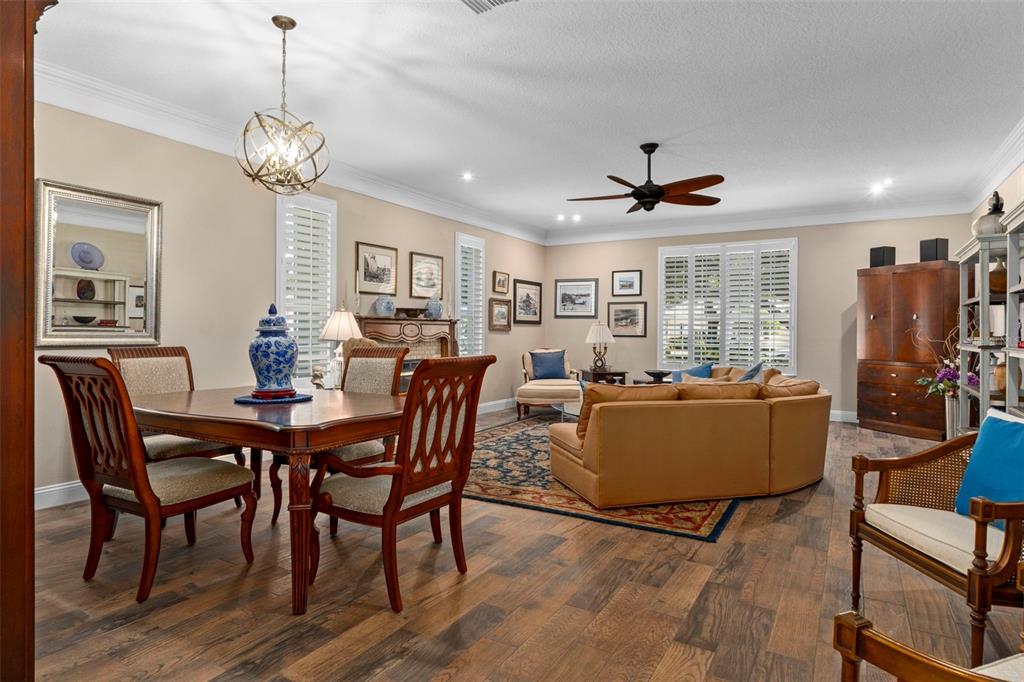 An open-concept living and dining area features wood flooring, a chandelier, and a sectional sofa — 6264 W GLYNBORNE LOOP, CRYSTAL RIVER, FL