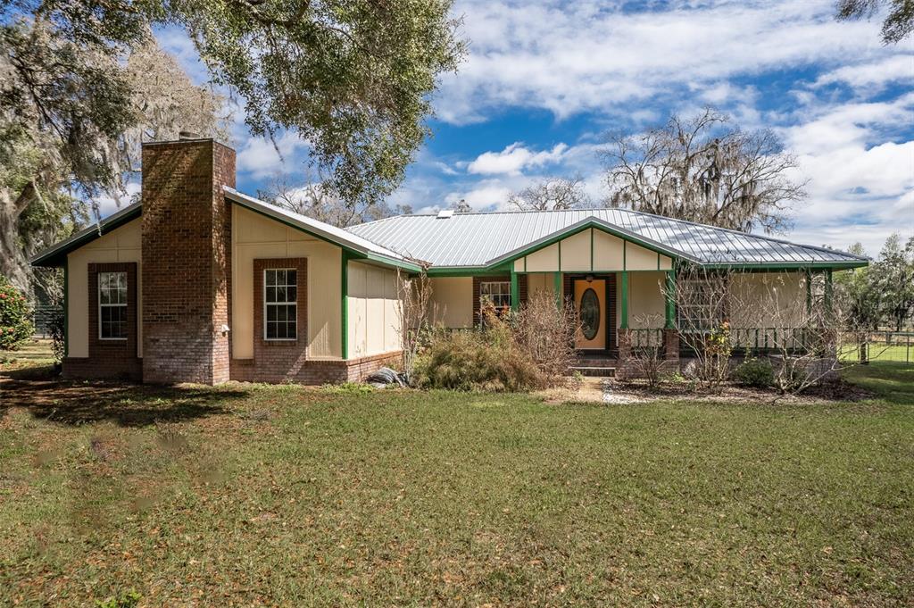 A white concrete block horse barn with a green metal roof and multiple stalls — 7115 SW 80TH AVENUE, OCALA, FL