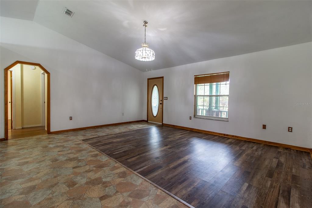 A living room features dark walls, wood-look flooring, a brick fireplace, and a brick bar — 7115 SW 80TH AVENUE, OCALA, FL