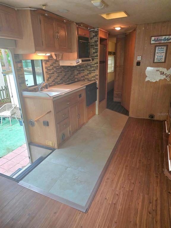 An RV kitchen features wood cabinets, a tiled backsplash, a sink, and a stove — 3000 CLARCONA ROAD UNIT 770, APOPKA, FL