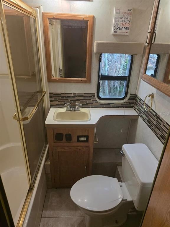 A small bathroom features a shower stall, a vanity with a sink, and a toilet — 3000 CLARCONA ROAD UNIT 770, APOPKA, FL
