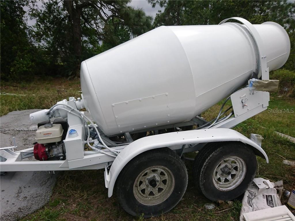 A white portable cement mixer sits on a dual-axle trailer in a grassy outdoor area — 99999 EASTERN AVENUE, ST CLOUD, FL