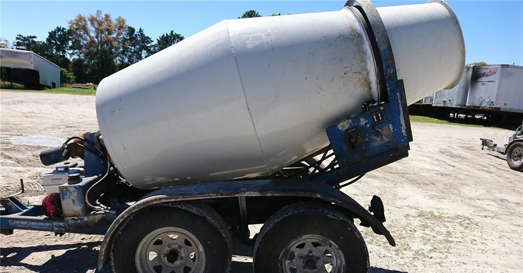 A portable concrete mixer on a dual-axle trailer sits on a dirt lot — 99999 EASTERN AVENUE, ST CLOUD, FL
