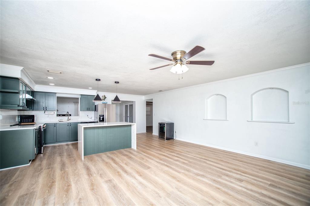 A kitchen with green cabinets and a white island opens into a living area — 989 8TH AVENUE NE, LARGO, FL