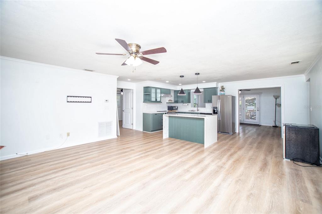 An open-concept kitchen with green cabinets and a center island overlooks a spacious living area — 989 8TH AVENUE NE, LARGO, FL