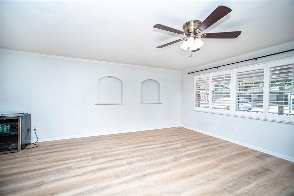 An empty room with light wood-look flooring, a ceiling fan, and two arched wall niches — 989 8TH AVENUE NE, LARGO, FL