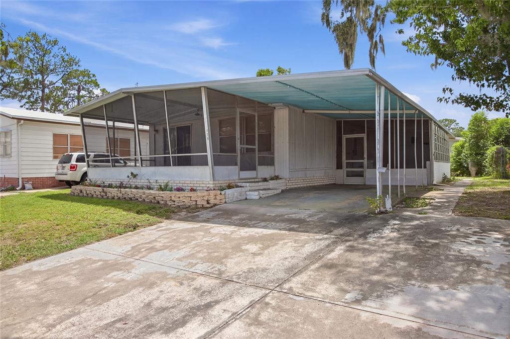 A mobile home features a large screened-in porch, a concrete driveway, and a metal carport — 110 MAPLE DRIVE, DEBARY, FL