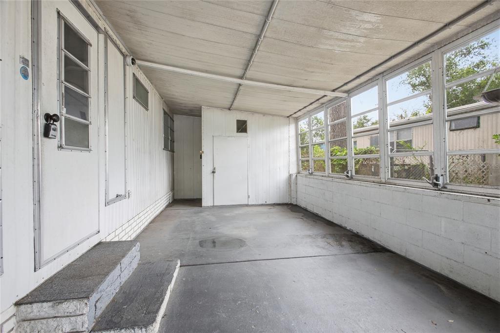 A covered concrete patio features white paneled walls, a door with steps, and large windows — 110 MAPLE DRIVE, DEBARY, FL