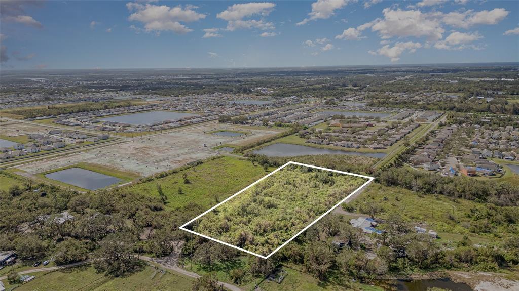 An aerial view shows a rectangular, undeveloped plot of land outlined in white — 12TH STREET SE, RUSKIN, FL
