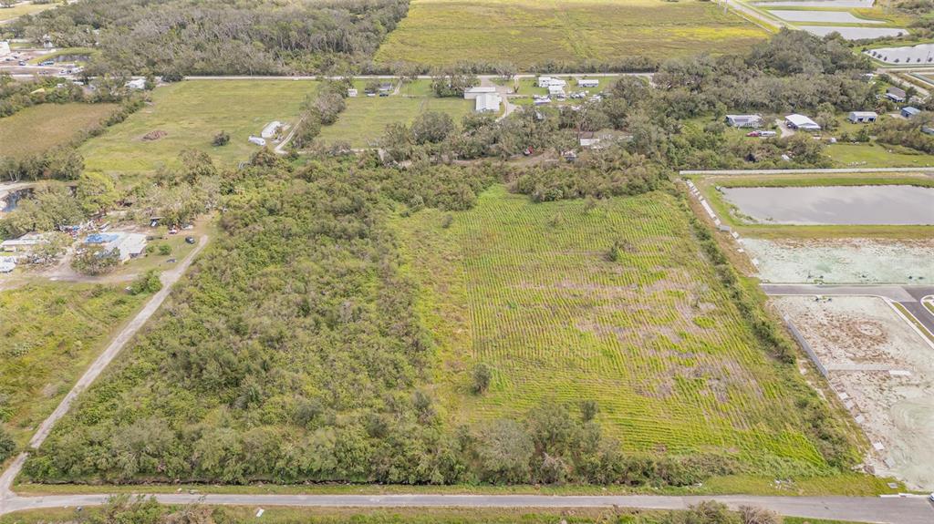 An aerial view shows a large, partially wooded vacant lot adjacent to a residential street — 12TH STREET SE, RUSKIN, FL