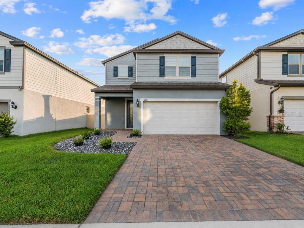 A two-story house features a light blue exterior, a brick driveway, and a two-car garage — 2704 VISTA VERDE LANE, KISSIMMEE, FL