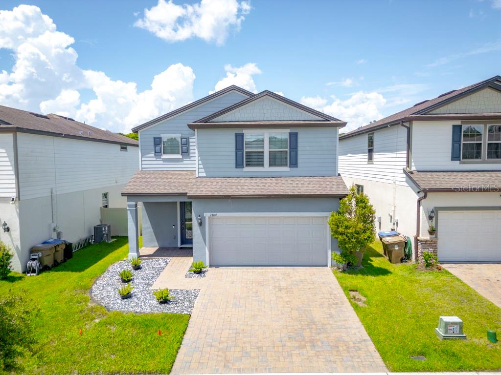A two-story suburban house with a light blue exterior, a two-car garage, and a paver driveway — 2704 VISTA VERDE LANE, KISSIMMEE, FL