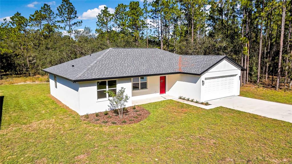 A single-story white stucco house with a gray shingled roof and a red front door — 8118 N SANTOS DRIVE, CITRUS SPRINGS, FL