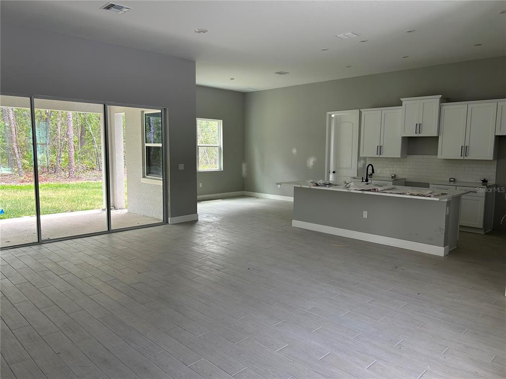 An open-concept kitchen and living area features light gray tile flooring and sliding glass doors — 3781 N BOXELDER WAY, BEVERLY HILLS, FL
