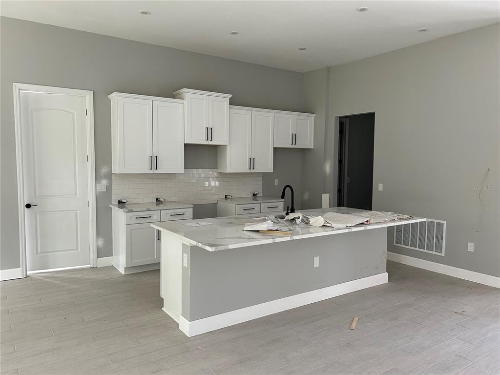 A kitchen features white cabinets, a marble-topped island, and light gray tile flooring — 3781 N BOXELDER WAY, BEVERLY HILLS, FL