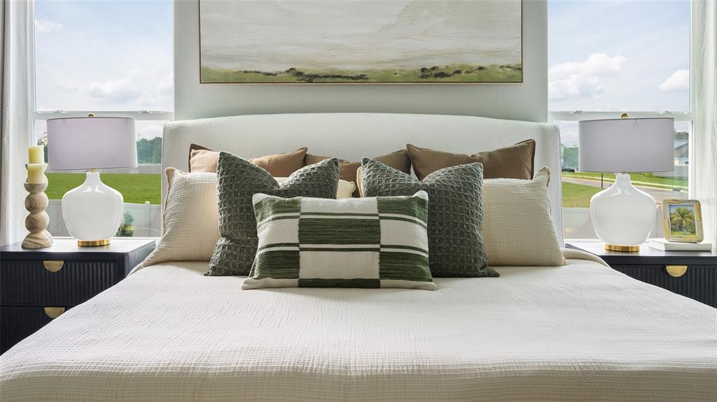 A bedroom features a white upholstered headboard, dark nightstands, and a green-accented bedding arrangement — 34620 SILENT PINE RUN, DADE CITY, FL