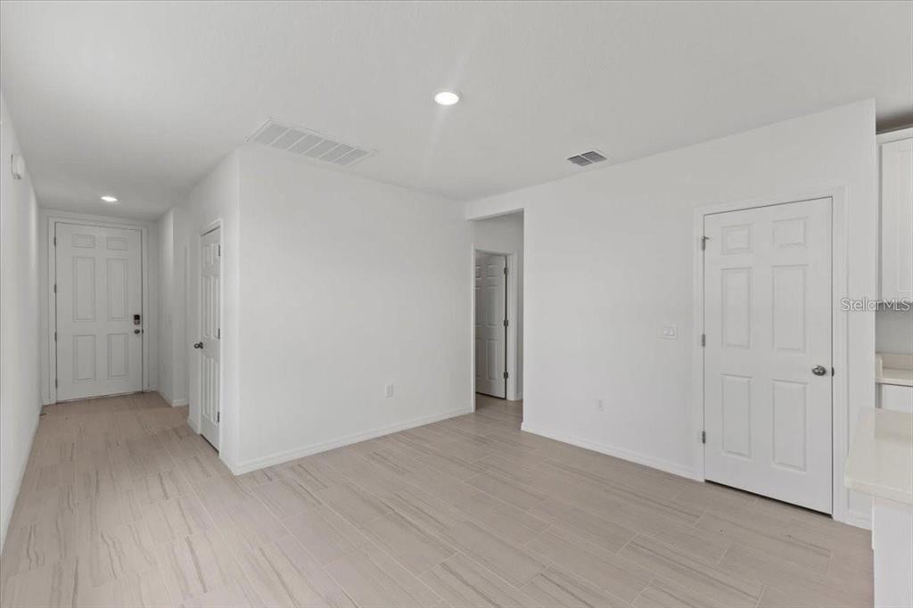 An interior view of a room with white walls, light tile flooring, and several doors — 3552 BROADWING BOULEVARD, POINCIANA, FL