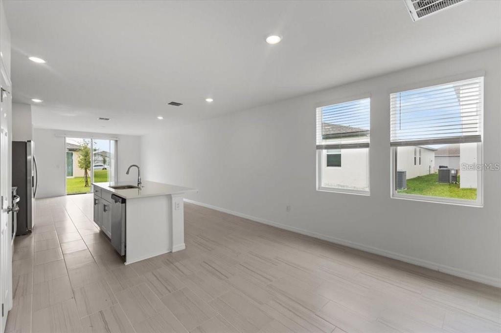A kitchen island with a sink sits in a bright, open-concept room with tile flooring — 3552 BROADWING BOULEVARD, POINCIANA, FL
