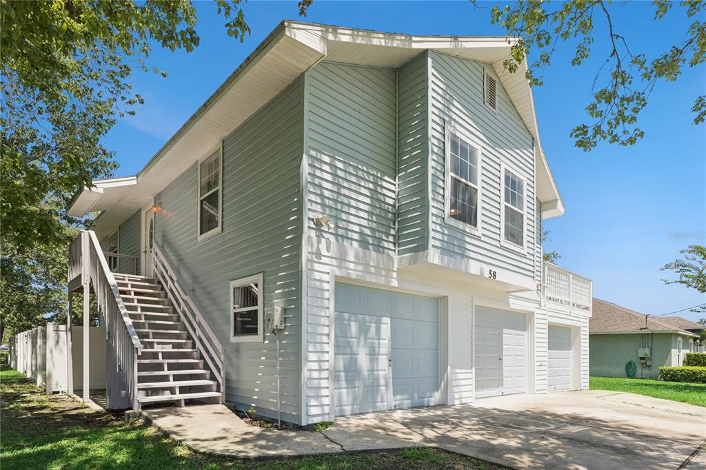 A two-story house with light blue siding, an external staircase, and a three-car garage — 58 KANKAKEE TRAIL, PALM COAST, FL