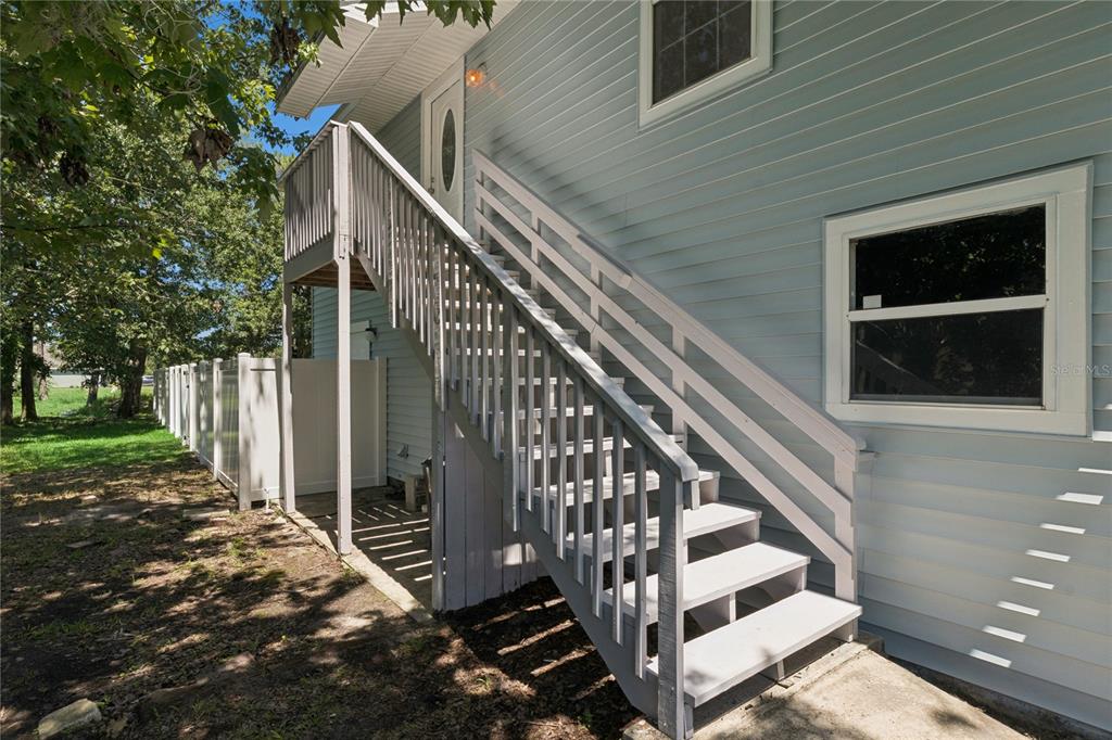 An exterior view of a light blue house featuring a wooden staircase leading to a door — 58 KANKAKEE TRAIL, PALM COAST, FL