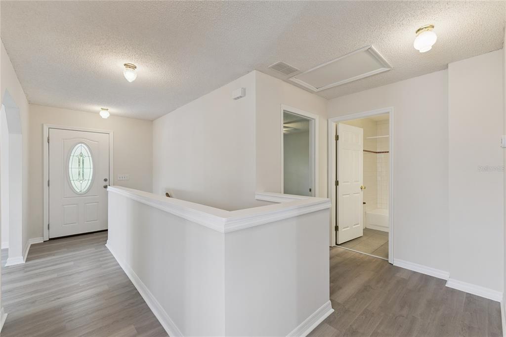 An interior view of a hallway with light gray flooring, white walls, and a staircase railing — 58 KANKAKEE TRAIL, PALM COAST, FL