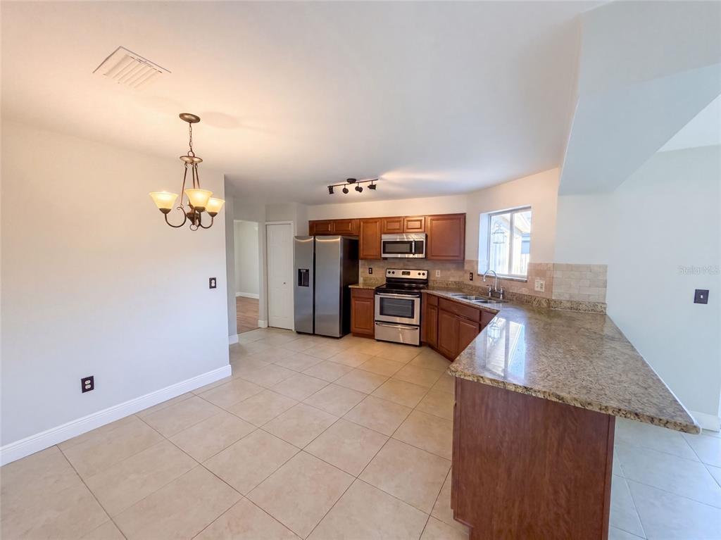 A kitchen with wood cabinets, granite countertops, stainless steel appliances, and tile flooring — 2330 FOGGY RIDGE PARKWAY, LAND O LAKES, FL