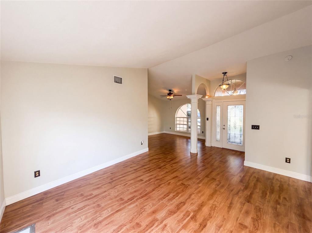 An open living area features wood-look flooring, a vaulted ceiling, and a glass-paneled front door — 2330 FOGGY RIDGE PARKWAY, LAND O LAKES, FL