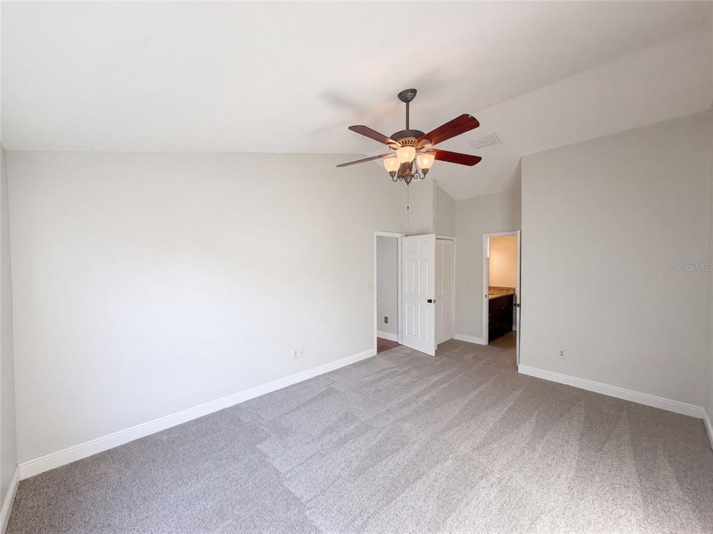 An empty bedroom features light gray walls, gray carpeting, a ceiling fan, and two doorways — 2330 FOGGY RIDGE PARKWAY, LAND O LAKES, FL
