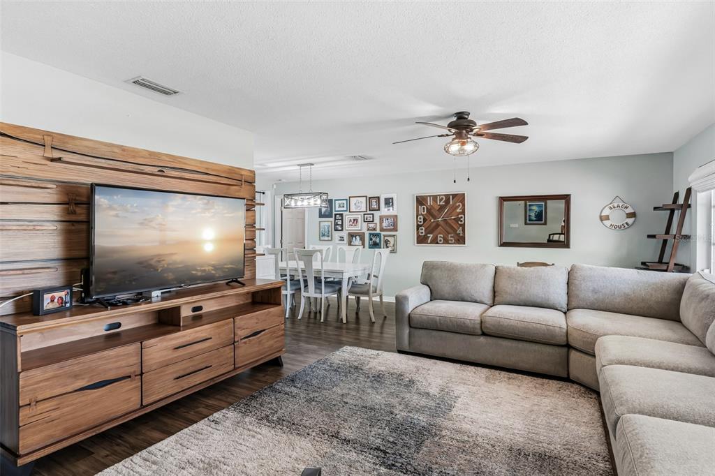 A living room features a wood-paneled media wall, a sectional sofa, and a dining area — 14570 TANGLEWOOD DRIVE, LARGO, FL