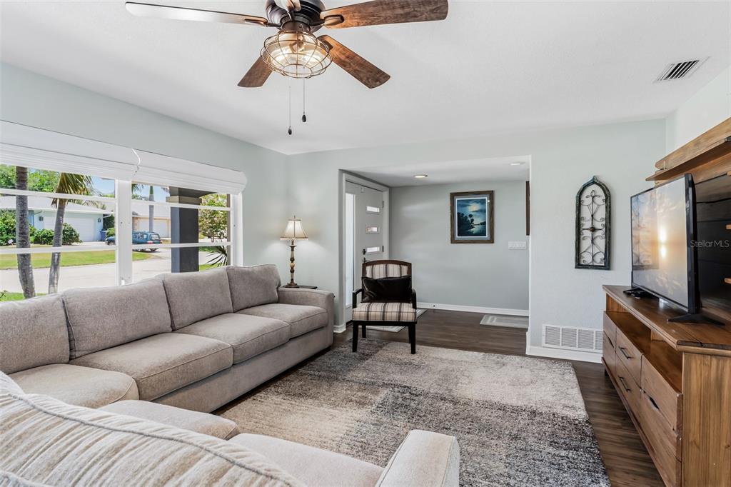 A living room features a gray sectional sofa, a patterned rug, and a ceiling fan — 14570 TANGLEWOOD DRIVE, LARGO, FL