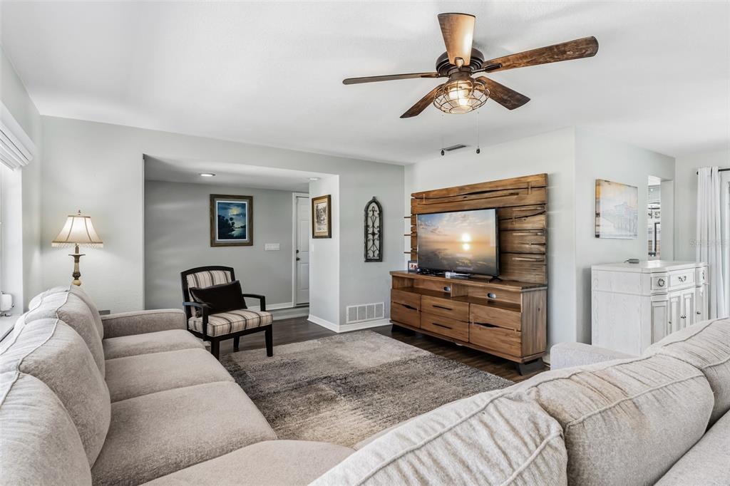 A living room features a sectional sofa, a wood media console, and a ceiling fan — 14570 TANGLEWOOD DRIVE, LARGO, FL