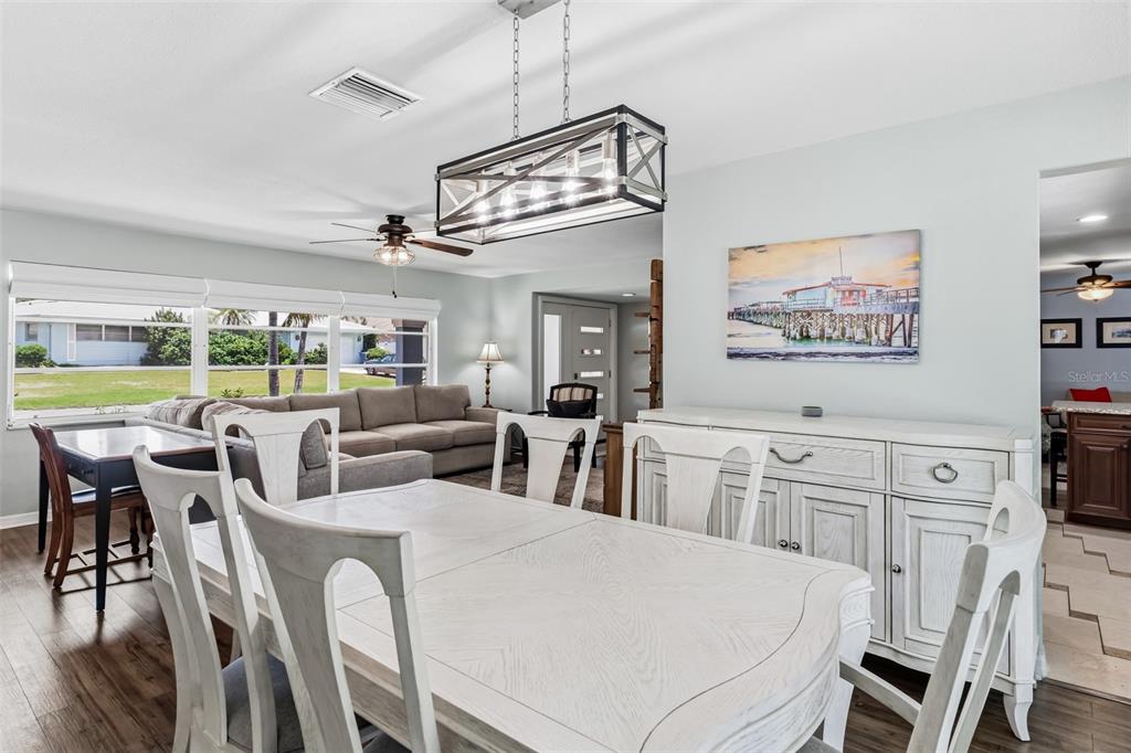 A dining room features a white table, matching chairs, and a rectangular farmhouse-style chandelier — 14570 TANGLEWOOD DRIVE, LARGO, FL
