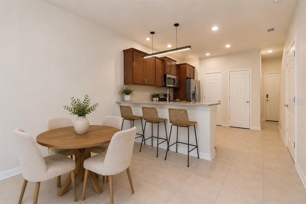 A kitchen with wood cabinets and a breakfast bar overlooks a dining area with chairs — 5368 SYLVESTER LOOP, TAMPA, FL