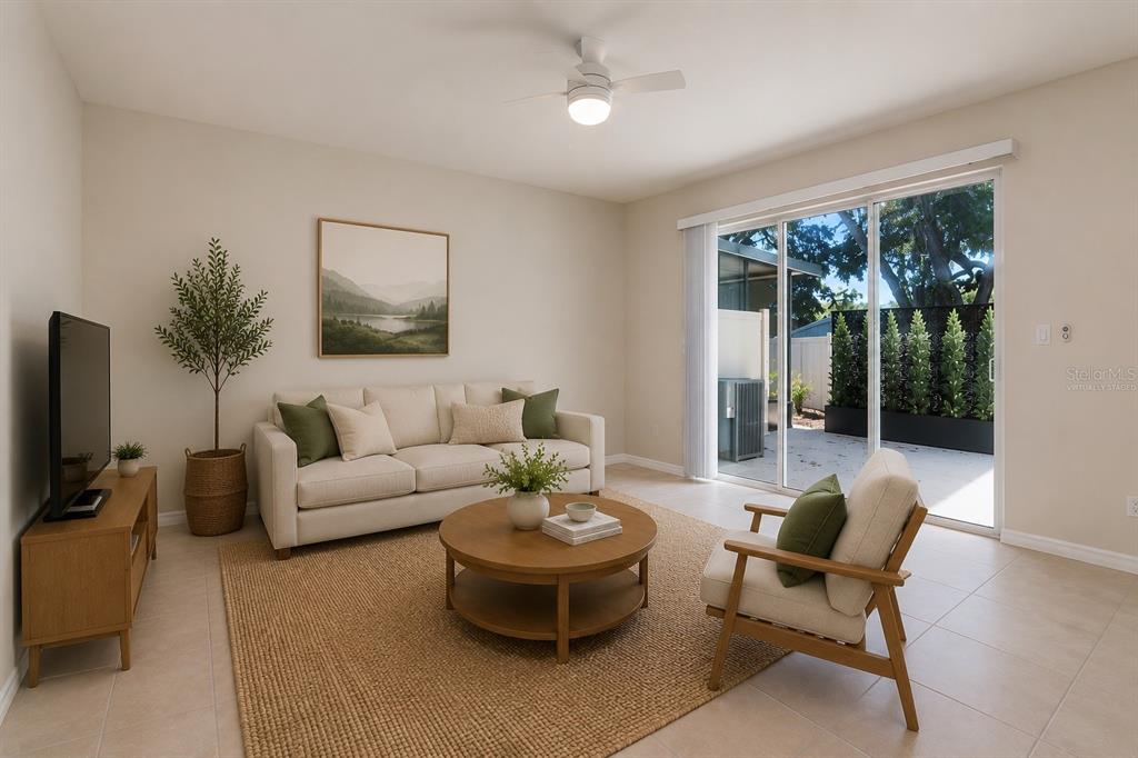 A living room features a sofa, round coffee table, armchair, and sliding glass doors to a patio — 5368 SYLVESTER LOOP, TAMPA, FL