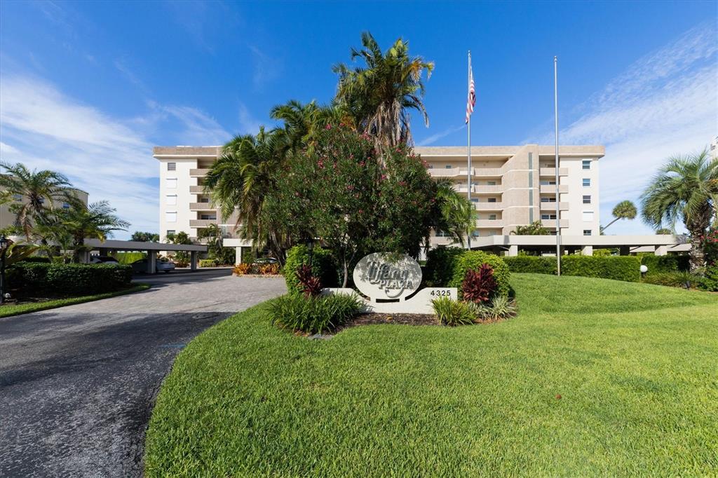 A multi-story apartment building stands behind a landscaped lawn with a prominent entrance sign — 4325 GULF OF MEXICO DRIVE UNIT 208, LONGBOAT KEY, FL