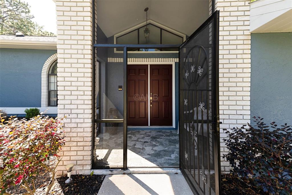 A front entryway features a screened porch, double doors, and a stone-tiled floor — 2298 W PINE RIDGE BOULEVARD, BEVERLY HILLS, FL