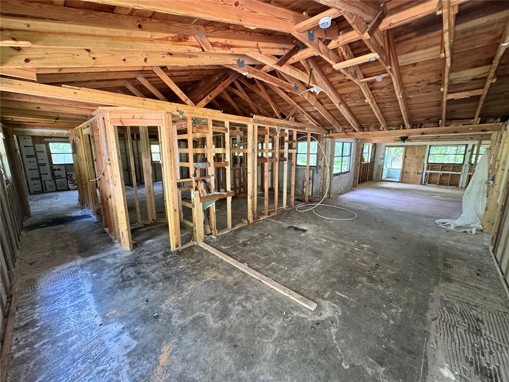 An interior view of a house under renovation with exposed wooden framing and concrete floors — 9010 MAIDEN LANE, ARIPEKA, FL