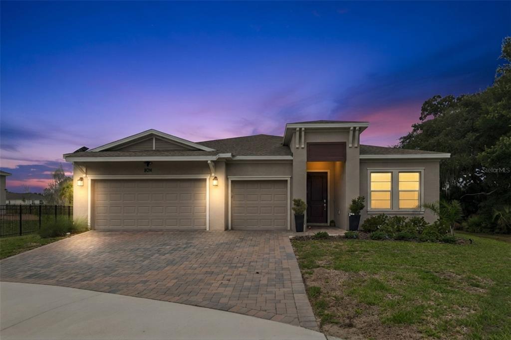A single-story house with a three-car garage and a paved driveway at dusk — 5361 DAGENHAM DRIVE, DAVENPORT, FL