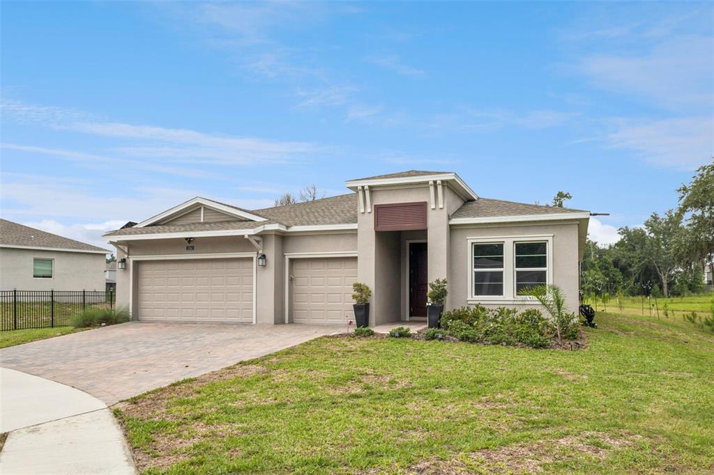 A single-story house with a three-car garage, stucco exterior, and a paved driveway — 5361 DAGENHAM DRIVE, DAVENPORT, FL
