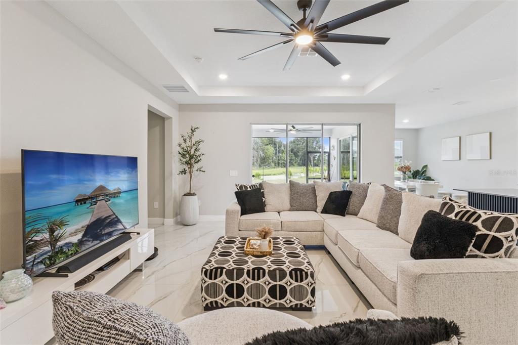 A living room features a large sectional sofa, patterned ottoman, and tile flooring — 5361 DAGENHAM DRIVE, DAVENPORT, FL