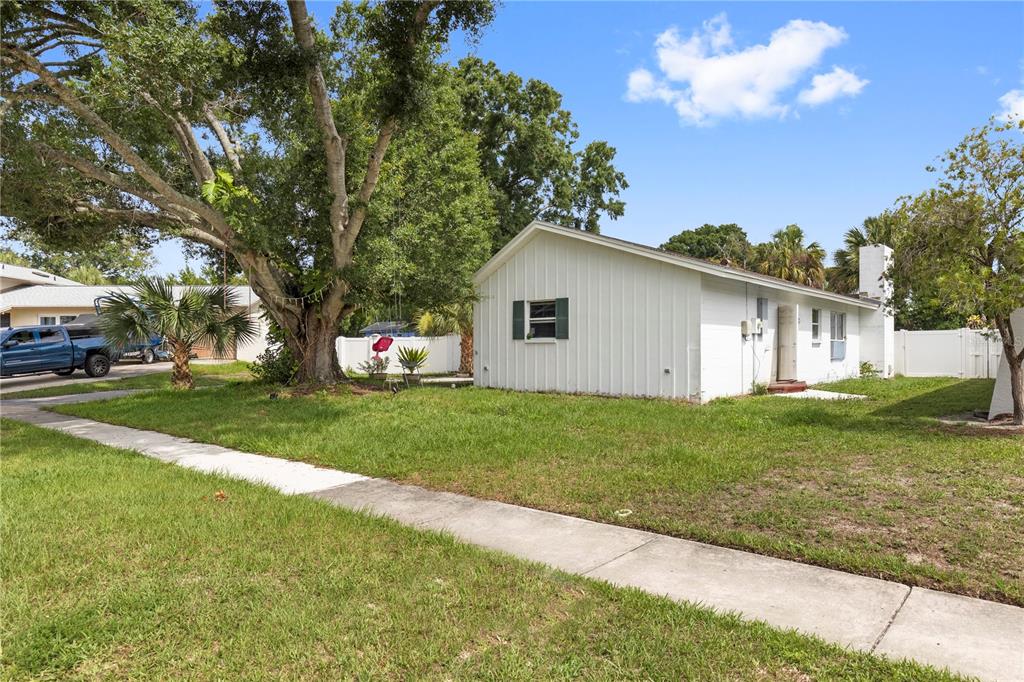 A white single-story house with a large tree in the front yard and a sidewalk — 7529 ARMAND CIRCLE, TAMPA, FL