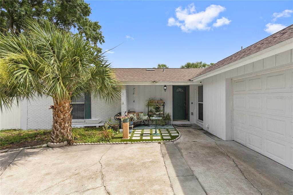 A white house with a palm tree, a concrete driveway, and a covered front entryway — 7529 ARMAND CIRCLE, TAMPA, FL