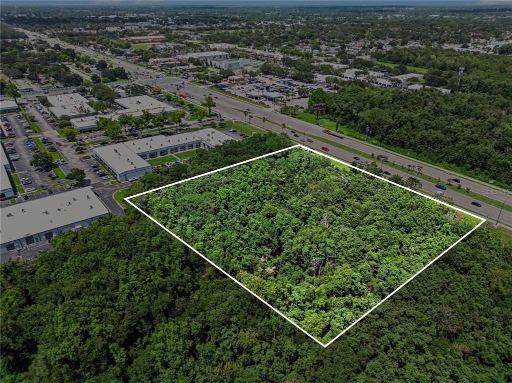 An aerial view shows a rectangular, wooded plot of land outlined in white — 6000 S SEMORAN BOULEVARD, ORLANDO, FL
