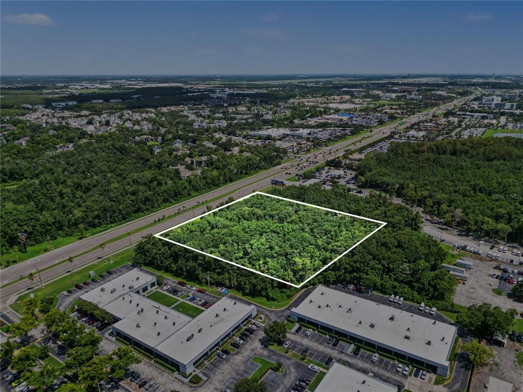 An aerial view shows a rectangular, wooded lot outlined in white between two commercial buildings — 6000 S SEMORAN BOULEVARD, ORLANDO, FL