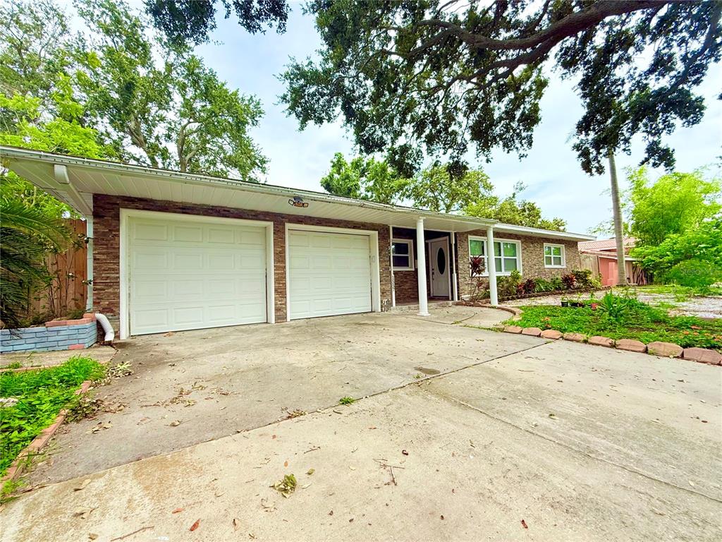 A single-story house features a two-car garage, stone facade, and a concrete driveway — 1557 ROBINSON DRIVE N, ST PETERSBURG, FL